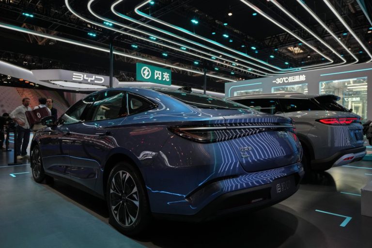Visitors chat as car models are displayed near a chamber with sub-zero temperatures to showcase the battery charging technologies from Chinese automaker BYD