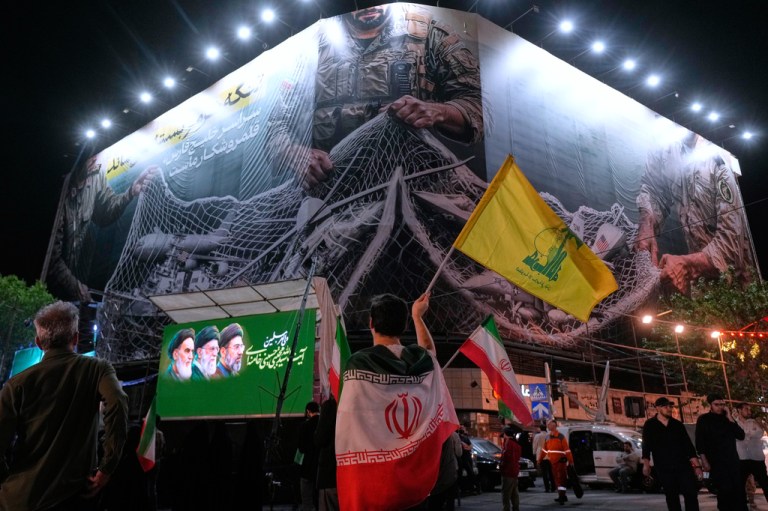 An Iranian demonstrator waves a flag of Lebanon's militant Hezbollah group under an anti-U.S. billboard