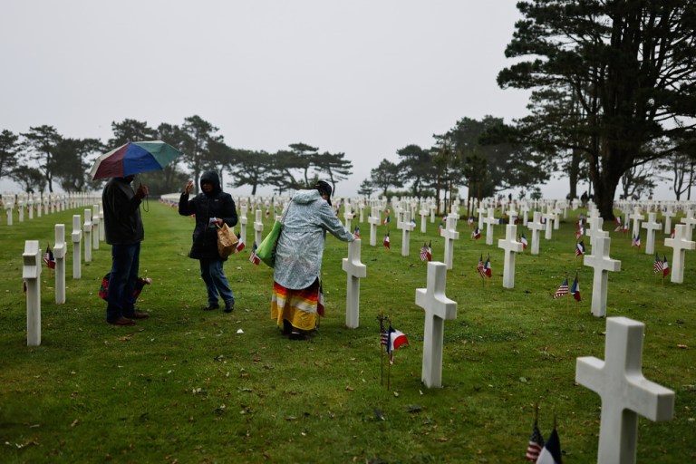 A woman stands next to headstones at the US cemetery to commemorate the 82nd anniversary of the D-Day landings, in Colleville-sur-Mer, Normandy, France, Saturday, June 6, 2026.