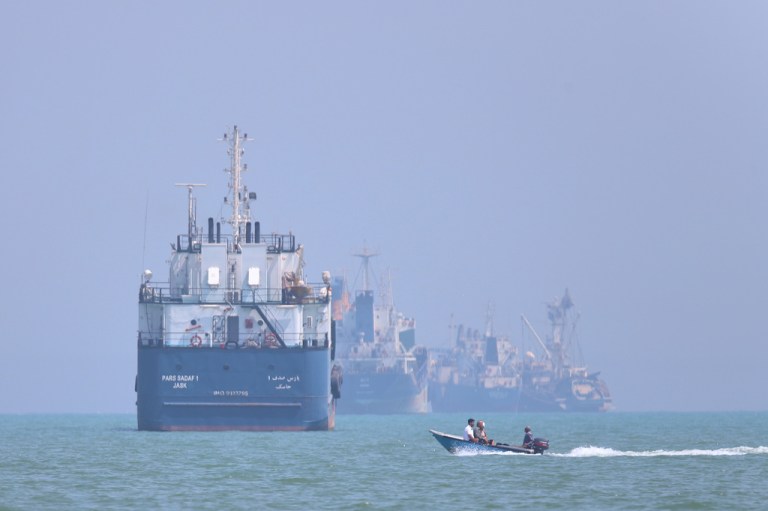 A small motorboat passes anchored vessels in the Strait of Hormuz.