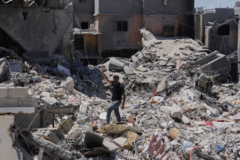 A man flashes the victory sign,as he stands on the rubble of destroyed houses that were recently hit in an Israeli airstrike in the southern port city of Tyre, Friday, June 12, 2026.