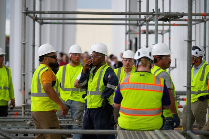 Workers wait for the rain to stop before resuming work to remove President Donald Trump's name from the John F. Kennedy Center for the Performing Arts in Washington, Friday, June 12, 2026.