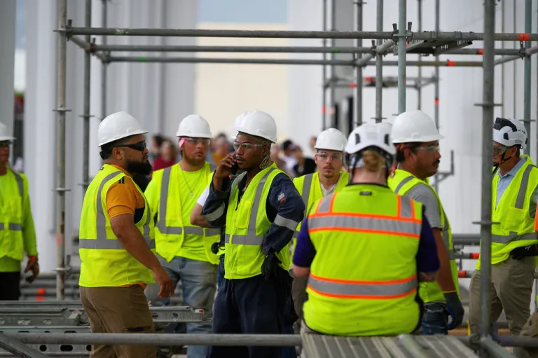 Workers wait for the rain to stop before resuming work to remove President Donald Trump's name from the John F. Kennedy Center for the Performing Arts in Washington, Friday, June 12, 2026.