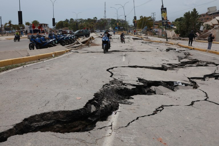 Motorcyclists ride along a road cracked by earthquakes that struck La Guaira, Venezuela, a day earlier, Thursday, June 25, 2026. (AP Photo/Javier Campos)