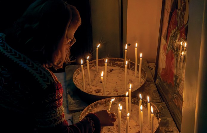 A woman lights a candle at Mar Elias Greek Orthodox Church in Damascus. In 2025, an attacker struck the church, killing 25. (Photo by Jordan Allott)