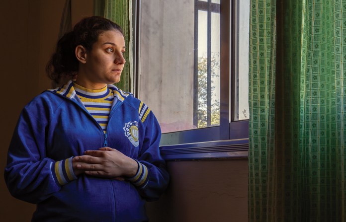 A Christian woman from villages near Sweida stands inside a church-run shelter in Khabab, in southern Syria. Fighting between Druze and Bedouin factions forced her family to flee with little warning, leaving their home destroyed. (Photo by Jordan Allott)