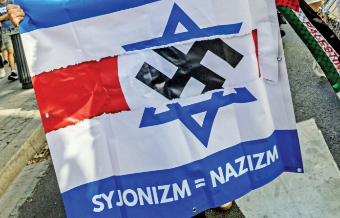 A protester in Warsaw holds a banner equating Zionism with Nazism, Sept. 9, 2025. (Neil Milton/SOPA Images/LightRocket/Getty)