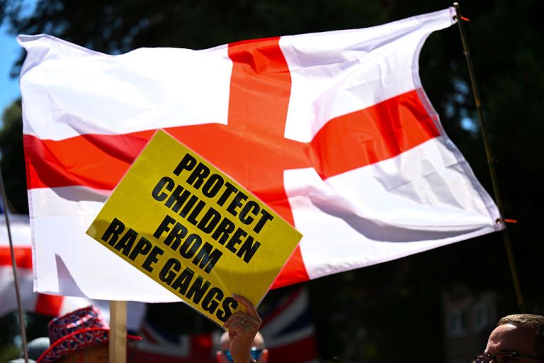 A sign stating 'Protect Children From Rape Gangs' is held by an anti illegal immigration protester outside The Roundhouse hotel, on August 09, 2025 in Bournemouth, England. Protesters and counter-protesters have gathered outside hotels being used to house asylum seekers in recent weeks, as tensions flare over the government's policies on illegal migration, which has reached record numbers this summer. Some far-right politicians and campaigners have faced allegations of fanning the flames by spreading misleading data on crimes committed by foreign nationals, following isolated reports of migrant arrests in connection to sexual assault charges. (Photo by Finnbarr Webster/Getty Images)