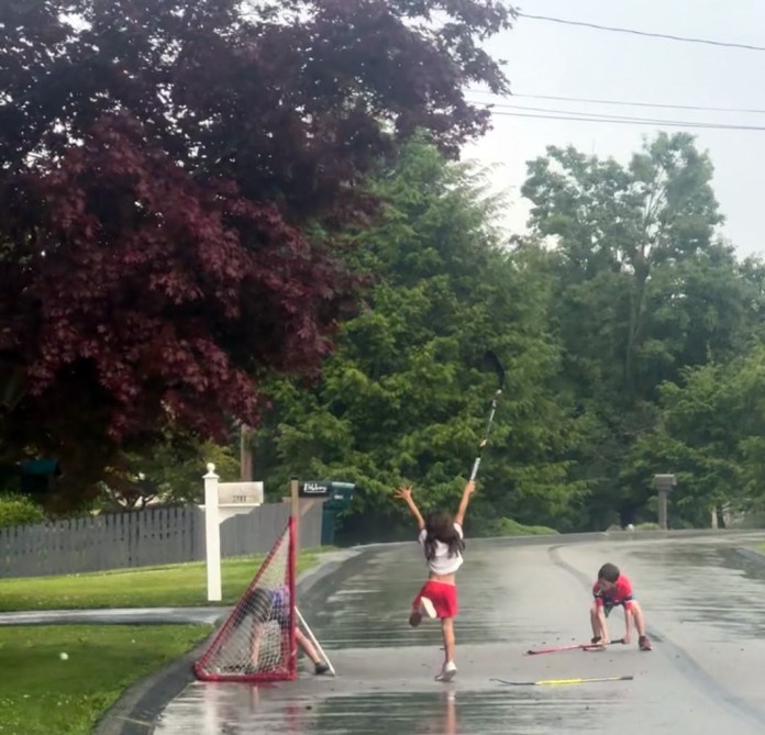 Children playing street hockey during one of the downpours. (Salena Zito)