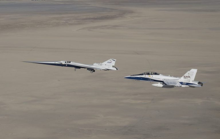 NASA’s X-59 flies above the Mojave Desert with a NASA F/A-18 research aircraft nearby, monitoring the X-59 during its first flight to NASA’s Armstrong Flight Research Center.