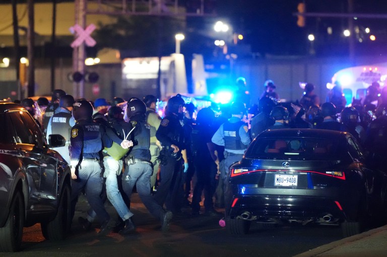 Law enforcement officers detain protesters outside Delaney Hall detention center.