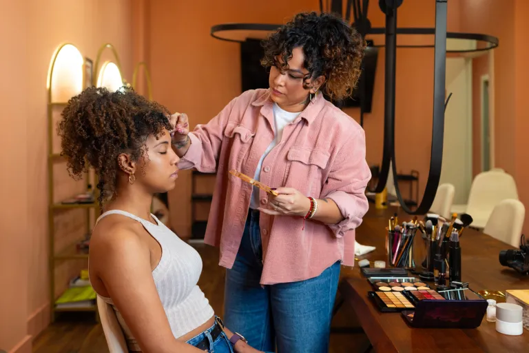 Professional makeup artist perfecting client's complexion during beauty salon makeover