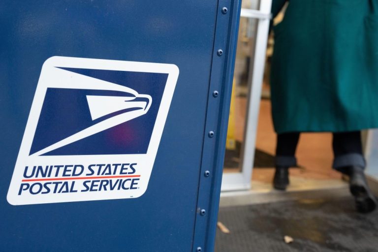 A United States Postal Service mail collection box is seen as a person walks in to the USPS building.
