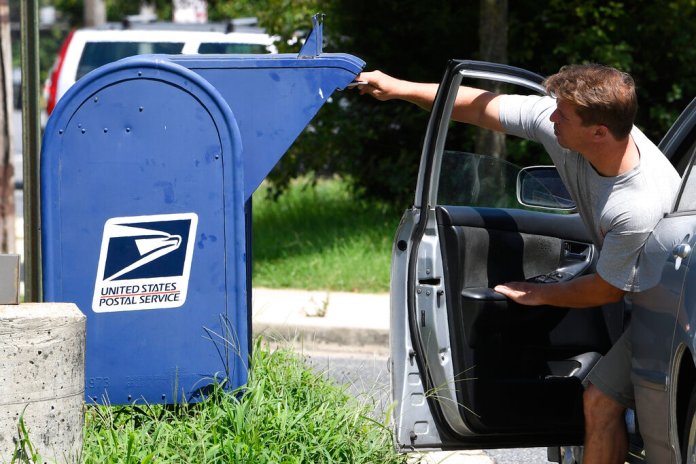 A person drops mail into a mailbox in Annapolis, Md., Tuesday, Aug. 18, 2020. (AP Photo/Susan Walsh)