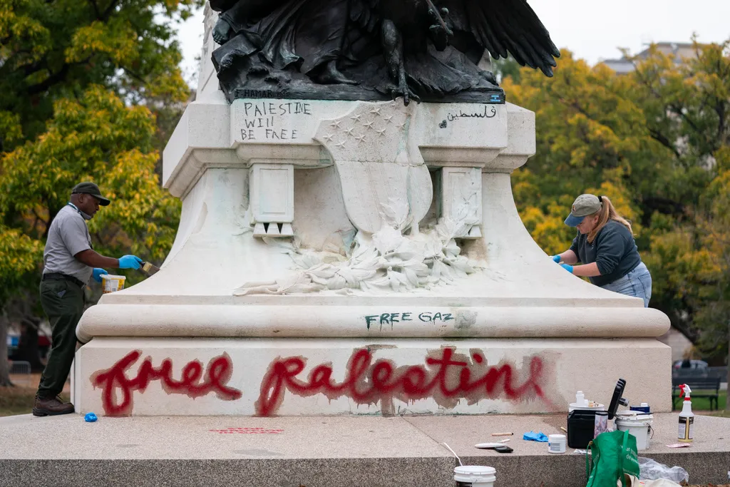 Workers remove graffiti from a statue in Lafayette Park
