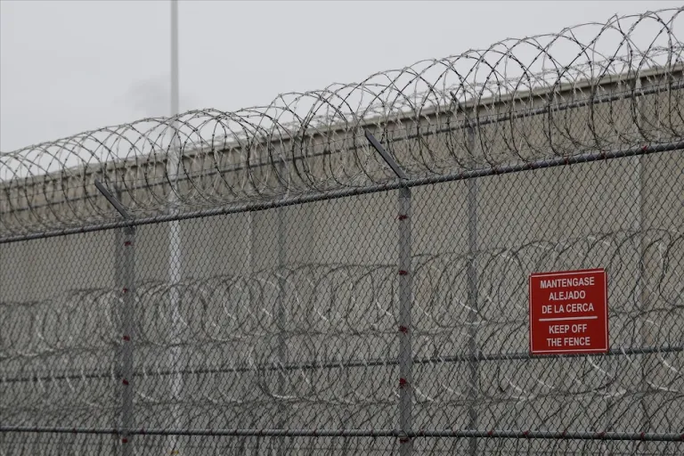 Barbed wire fencing is shown behind a sign in English and Spanish in a recreation yard used by detainees during a media tour of the Immigration and Customs Enforcement detention center, Dec. 16, 2019, in Tacoma, Wash. (AP Photo/Ted S. Warren)