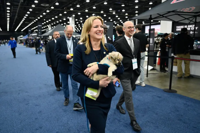 Michigan Secretary of State Jocelyn Benson, front, walks the floor at the Detroit Auto Show as she carries her newly adopted puppy, Lily, which she adopted earlier in the day at the show, Wednesday, Jan. 14, 2026, in Detroit.