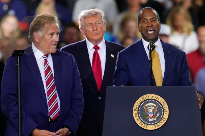 President Donald Trump and Senate candidate Mike Rogers listen as Rep. John James, R-Mich., speaks at an event at the General Motors Proving Ground Monday, July 27, 2026, in Milford, Mich.
