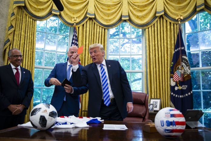 U.S. President Donald Trump, right, displays a referee red card to members of the media as Gianni Infantino, president of FIFA, center, and Carlos Cordeiro, president of the United States Soccer Federation, smile in the Oval Office of the White House in Washington, D.C., U.S., on Tuesday, Aug. 28, 2018. The 2026 FIFA World Cup will be held in the United States, Canada, and Mexico. Photographer: Al Drago/Bloomberg via Getty Images