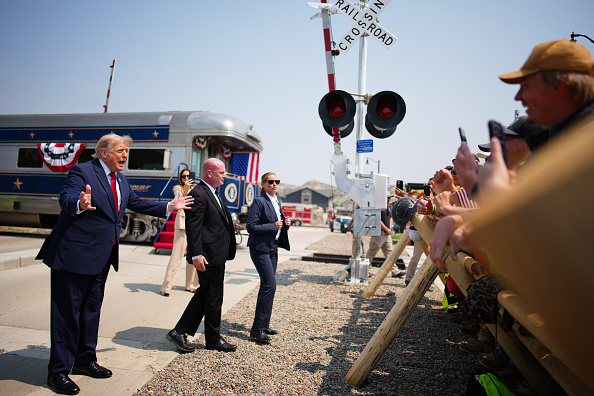 President Donald Trump greets onlookers after arriving in a Freedom250-themed train ahead of a dedication ceremony for the Theodore Roosevelt Presidential Library.