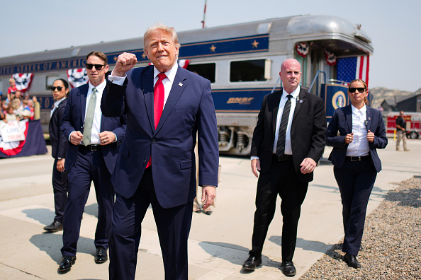 President Donald Trump greets onlookers after arriving in a Freedom250-themed train ahead of a dedication ceremony for the Theodore Roosevelt Presidential Library.