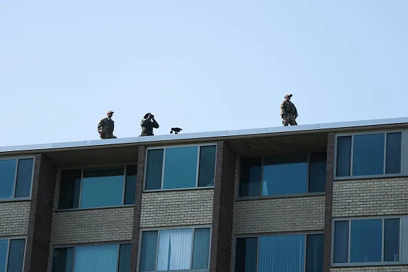 WASHINGTON, DC - JULY 02: Law enforcement members stand on the roof of a nearby apartment building before the arrival of U.S. Secretary of War Pete Hegseth at Meridian Hill Park on July 02, 2026 in Washington, DC. Hegseth and other members of U.S. President Donald Trump's administration visited the park to speak to guard members and to tout the DC Safe And Beautiful Task Force.