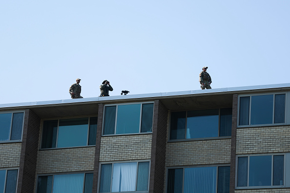 WASHINGTON, DC - JULY 02: Law enforcement members stand on the roof of a nearby apartment building before the arrival of U.S. Secretary of War Pete Hegseth at Meridian Hill Park on July 02, 2026 in Washington, DC. Hegseth and other members of U.S. President Donald Trump's administration visited the park to speak to guard members and to tout the DC Safe And Beautiful Task Force.