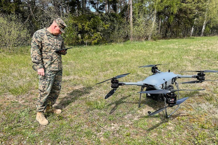 A U.S. marine service member stands next to a TRV 150 drone.