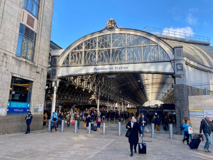 London, England, UK - December 19, 2024: The main entrance to Paddington Train Station in London. People can be seen entering and leaving the busy railway station on a sunny day.