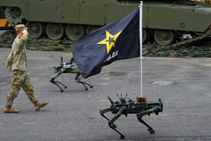 Robot dogs walk past the reviewing stand during a military parade.