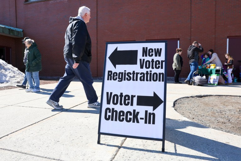 A sign for new voter registration is seen outside a polling location at Pinkerton Academy in Derry, N.H.