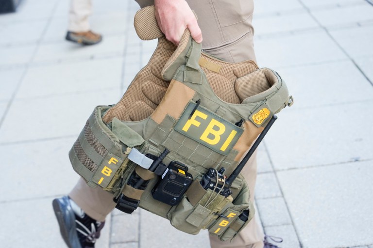 An FBI agent carries a vest out the front entrance of ex-Trump national security adviser John Bolton's Washington office, Friday, Aug 22, 2025. (AP Photo/Julia Demaree Nikhinson)