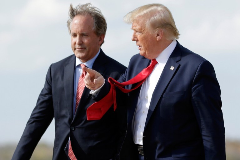 Donald Trump, right, with his red tie blowing in the wind, and Ken Paxton, left.