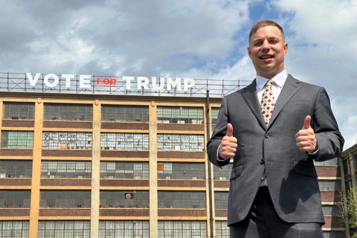 Anthony Constantino, a Republican candidate for Congress, stands in front of a "Vote for Trump" sign on the roof of his printing company, Sticker Mule, in Amsterdam, New York, Thursday, April 16, 2026. (AP Photo/Michael Hill)