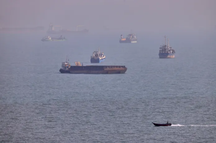 A small boat sails past cargo ships and other commercial vessels in the Strait of Hormuz.