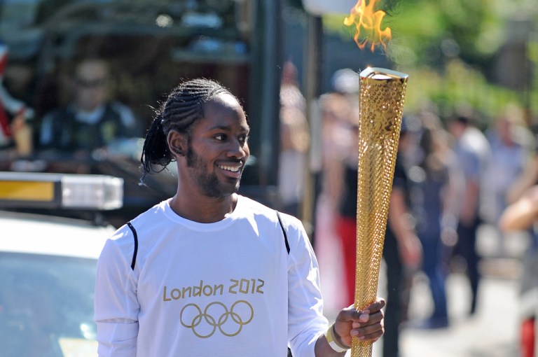 Torchbearer Jason Arday carries the Olympic Flame on the Torch Relay leg between Sutton and Merton, in London, July 23, 2012.