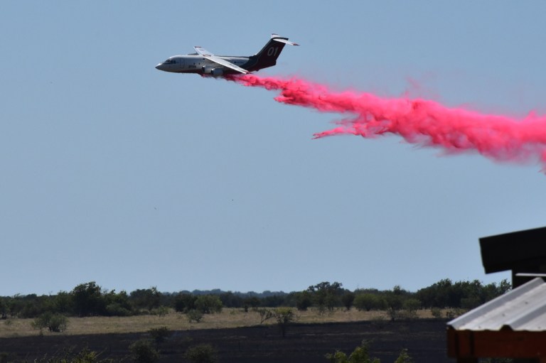A tanker aircraft dumps fire retardant on a field southwest of Salado, Texas, Wednesday, Aug. 12, 2026, after a military helicopter crashed and sparked a grass fire.