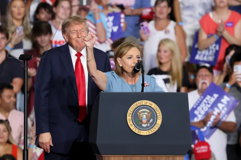 President Donald Trump watches Sen. Darline Graham at a rally.