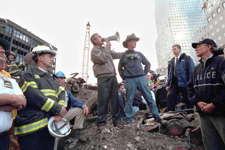 President George W. Bush speaks to rescue workers, firefighters and police officers from the rubble of Ground Zero September 14, 2001 in New York City. Standing with Bush is retired firefighter Bob Beckwith and at (R) is New York Governor George Pataki. (Eric Draper/White House/Getty Images)