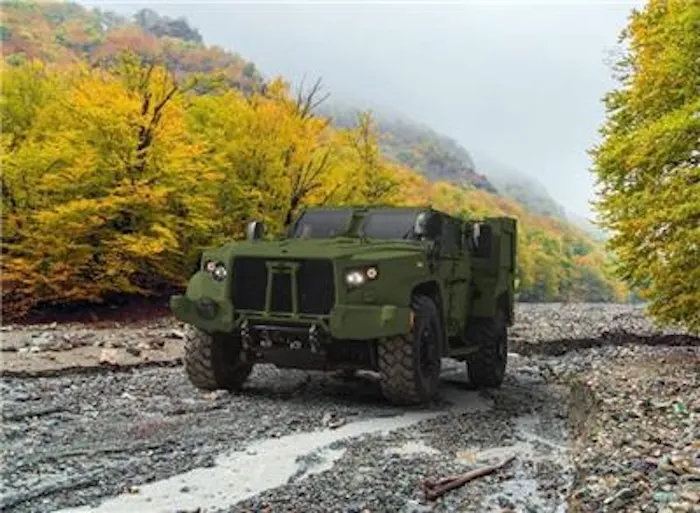 Green off-road, military, jeep-like truck called Joint Light Tactical Vehicle with trees surrounding it.
