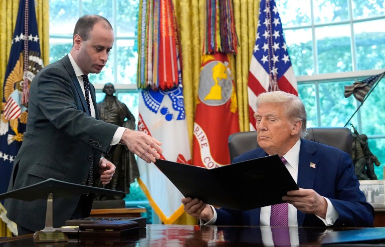 White House staff secretary Will Scharf (left) hands President Donald Trump an executive order to sign in the Oval Office on Sept. 5, 2025. (Alex Brandon/AP)