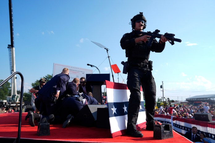 Republican presidential candidate former President Donald Trump is covered by U.S. Secret Service agents at a campaign rally.