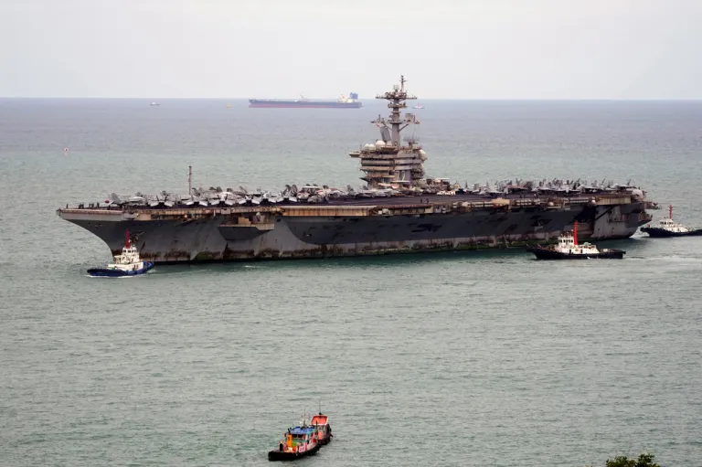Tug boats greet the U.S. Navy aircraft carrier USS Abraham Lincoln