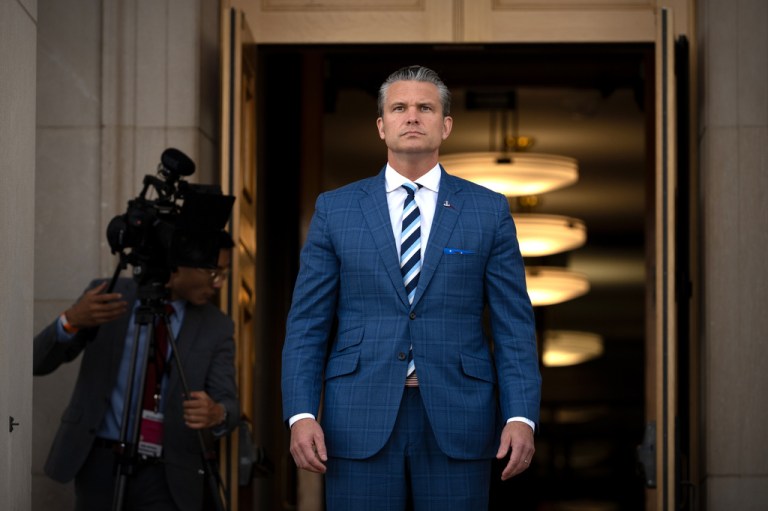 War Secretary Pete Hegseth walks forward looking stern as he readies for diplomatic talks.