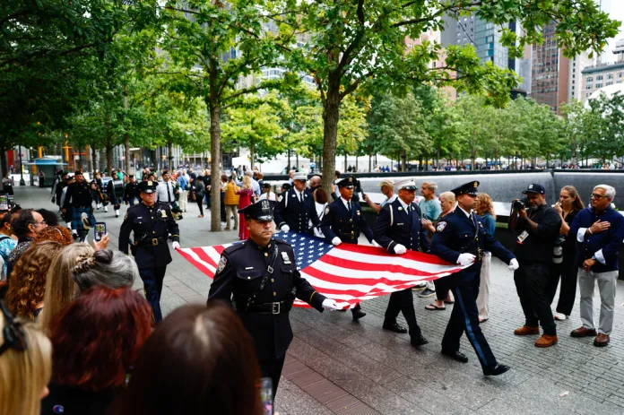 Law enforcement officers carry a U.S. flag during a ceremony commemorating the 25th anniversary of the Sept. 11, 2001, attacks.