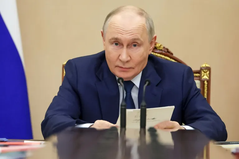 Balding Russian President Vladimir Putin sits in blue suit.