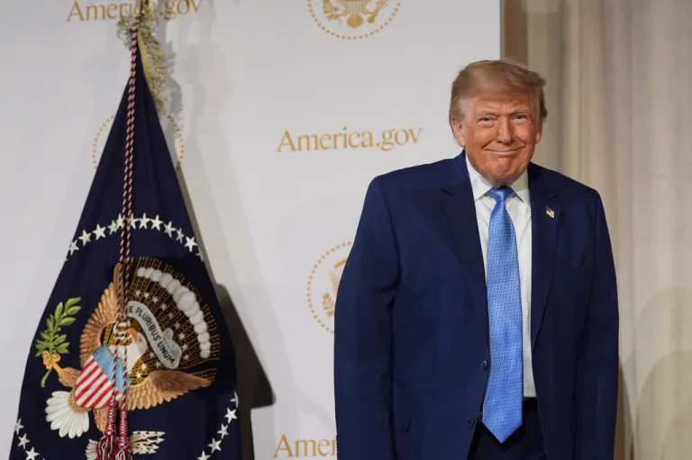 President Donald Trump throws the camera a sly smile on stage at the Andrew W. Mellon Auditorium in Washington.
