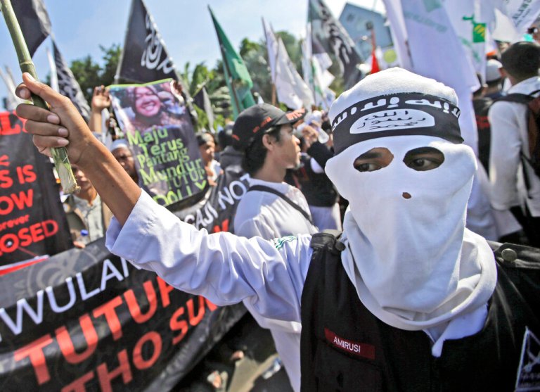 In this June 18, 2014, file photo, a man wears a headband showing the Islamic State group's symbol during a protest calling for the closure of a local prostitution complex in Surabaya, Indonesia. (AP Photo/Dita Alangkara, File)
