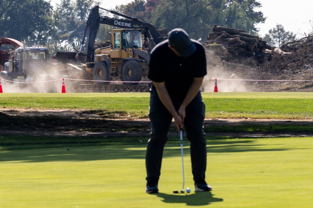 Crews remove cut-down trees from East Potomac Golf Links as golfers continue to use the course.