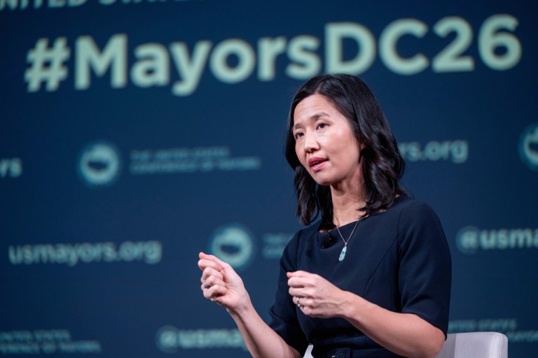 #MayorsDC26 is written above Boston Mayor Michelle Wu's head on the screen behind her as she speaks during the 94th Winter Meeting of the U.S. Conference of Mayors.